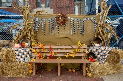 Fall photo booth setup with bench, hay bales, and autumn decorations
