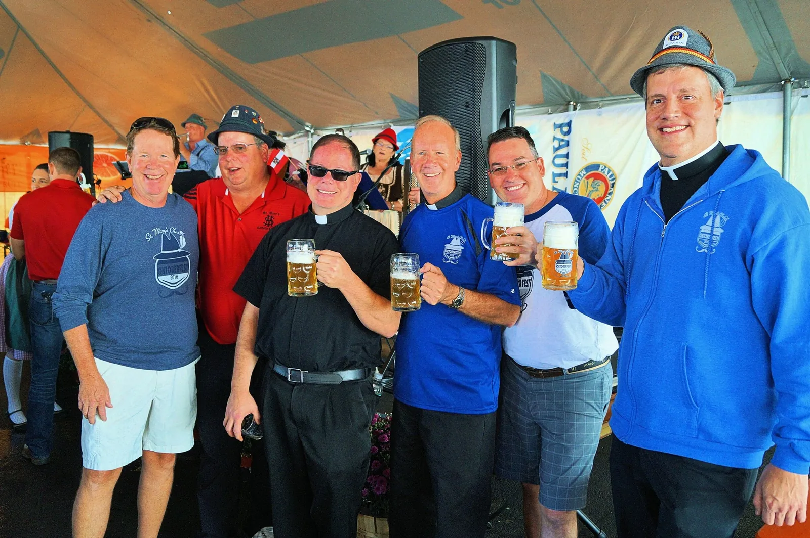 Priests and parishioners holding steins at Oktoberfest