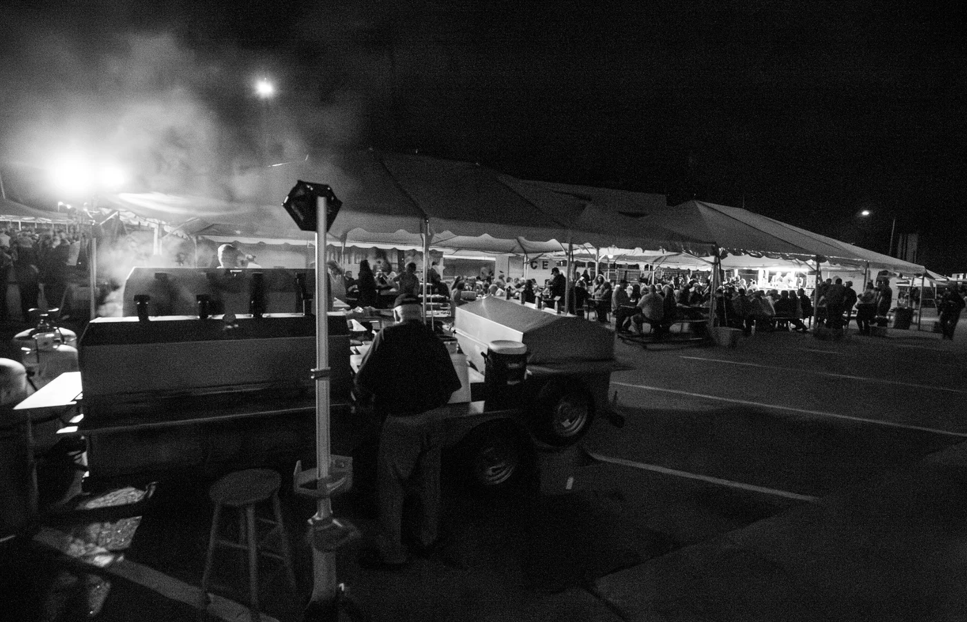 Smoky grills, food tents, volunteers, and guests at St. Mary’s Oktoberfest at night