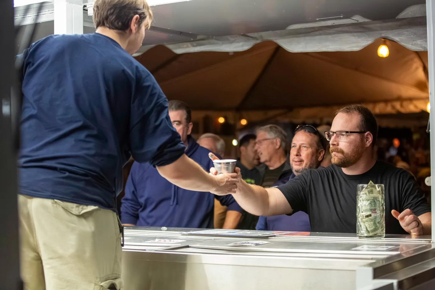 Volunteer serving a guest from the beer trailer